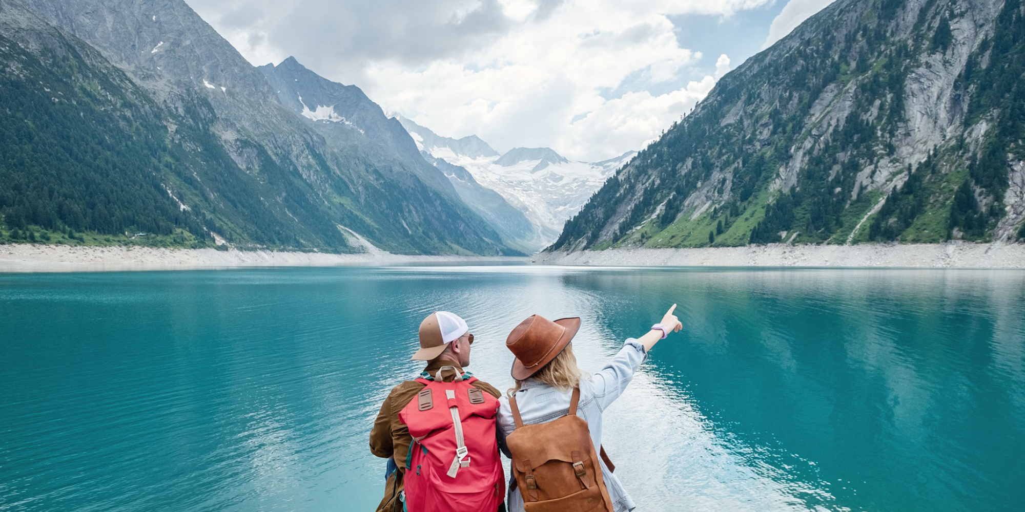 A young couple looking at a beautiful lake surrounded by mountains