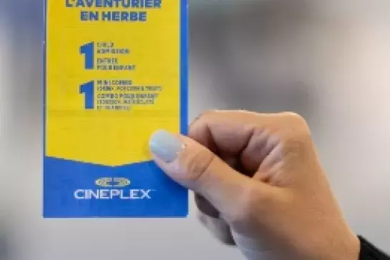 Hand with light blue nailpolish holding a cineplex ticket for 1 child adventure