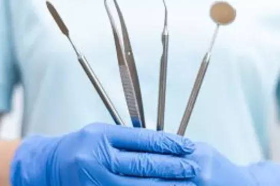 Dentist holding dental equipment in front of his body.